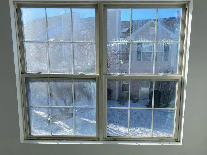 Double-hung windows with fogged, streaked glass from failed seals, before repair