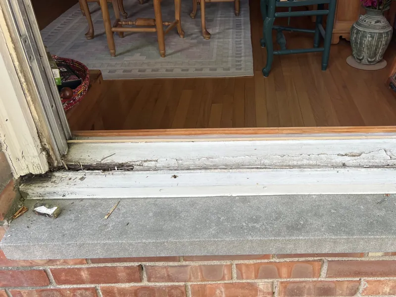 Rotted, peeling window sill at the corner of the frame