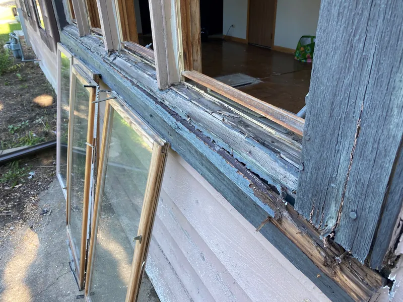 Old wood windows with peeling paint and weathered, rotted wood