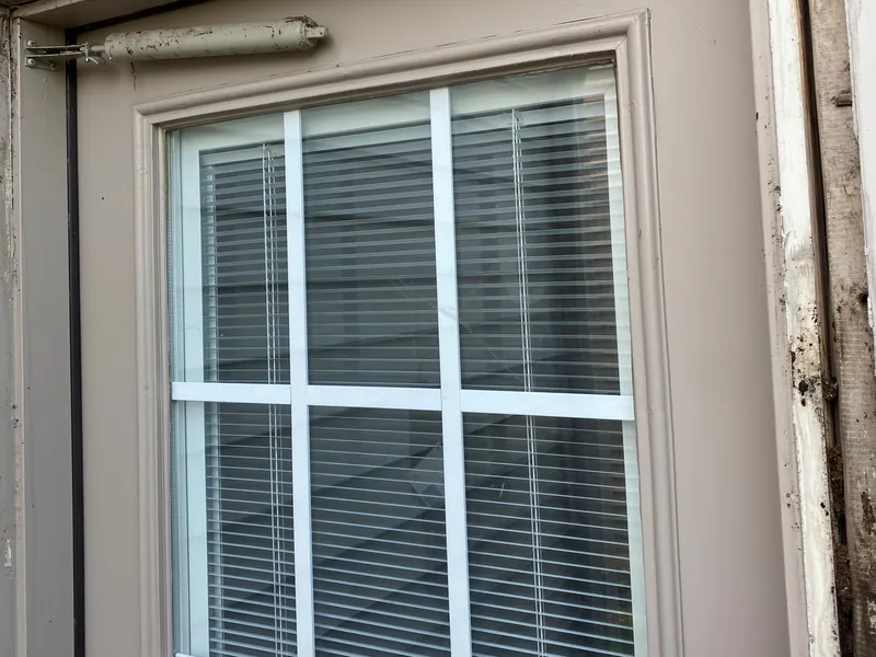 Crack in the glass of an entry door with blinds between the glass